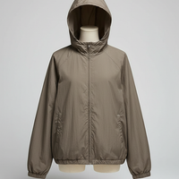 Orange transparent hooded jacket, model posing outdoors.