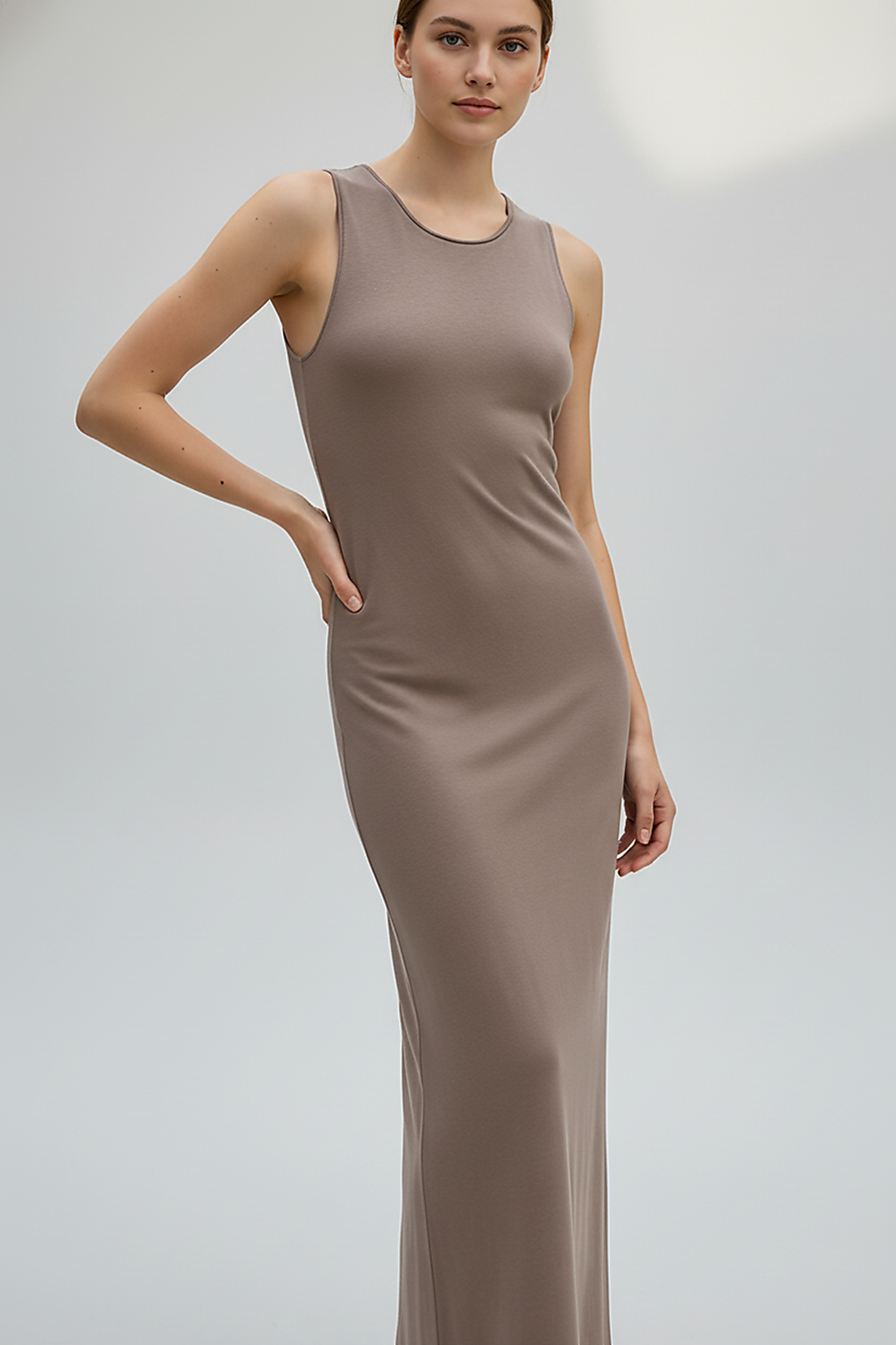 Brown sleeveless knitted dress, side view on model.