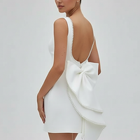 White mini dress with pearl bow detail, front view on model.