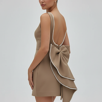 White backless mini dress with pearl bow, back view on model.