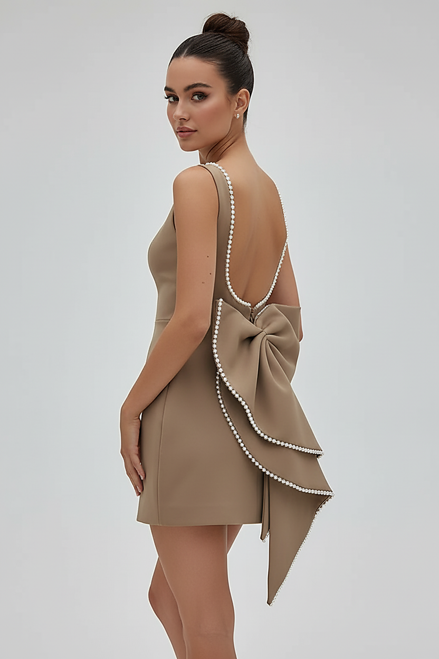 White backless mini dress with pearl bow, back view on model.