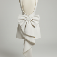 White mini dress backless design with pearl bow, close-up.