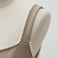 White mini dress with backless pearl bow, back view on model.