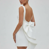 White mini dress with bow and pearl detail, front view on model.