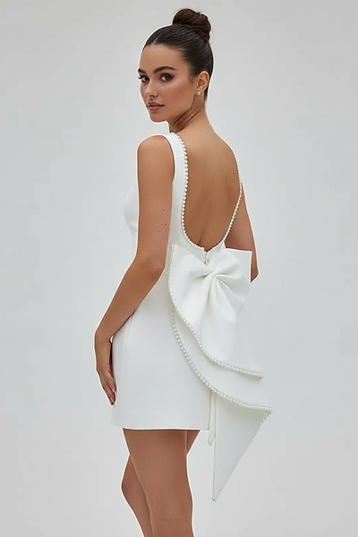 White mini dress with bow and pearl detail, front view on model.